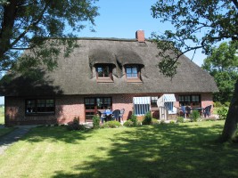 Gartenansicht auf das mit Reet gedeckte Friesenhaus, Liegewiese Terrasse, Strandkorb, Liegen, Tisch und Stühle. / Ferienhaus "Ferienhaus Neukoog II" in Nordstrand