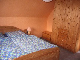 Gemütliches Schlafzimmer mit zusätzlichem Kinderbett. Ein Fernseher ist vorhanden. / Ferienwohnung "Ferienwohnung Hansen" in Husum