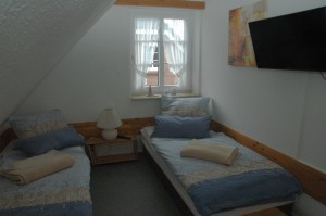 Schlafzimmer mit Einzelbetten und Fernseher / Ferienhaus "Muschelsucher 2" in Nordstrand-Norderhafen