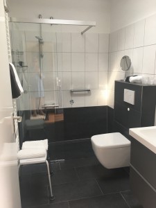 Bad mit einer begehbaren Dusche, einem modernen WC und einem großen beleuchteten Spiegel. / Ferienhaus "Bungalow Kleine Auszeit" in Husum